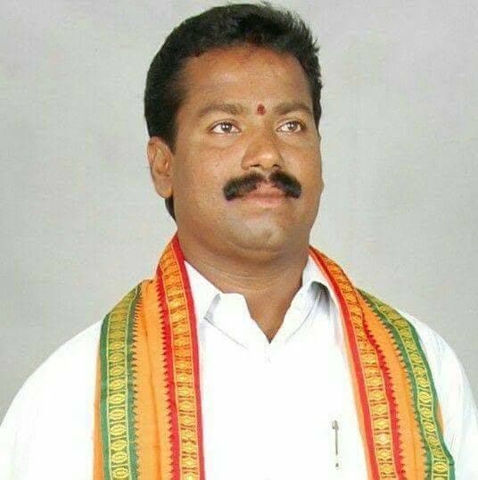 Portrait of Mogarala Suresh in a white shirt and a saffron and green party scarf